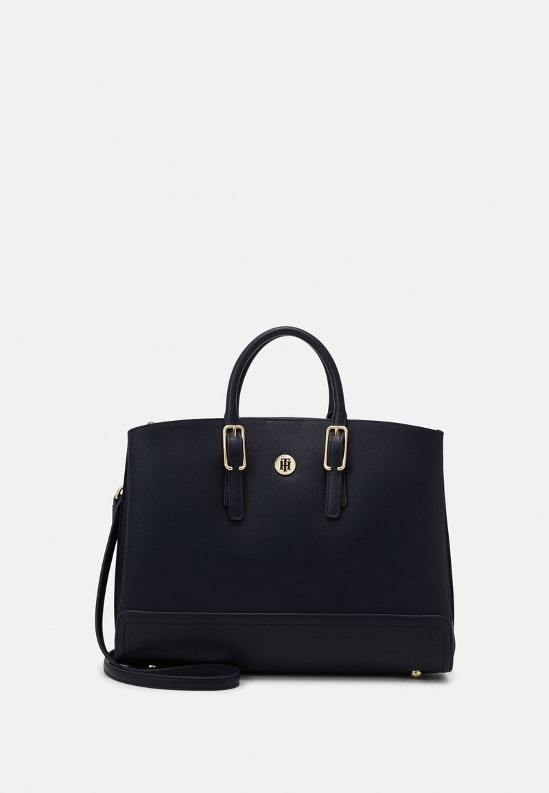 Navy handbag with textured surface and gold-tone hardware. Features dual handles, an adjustable shoulder strap, and a logo detail on the front.