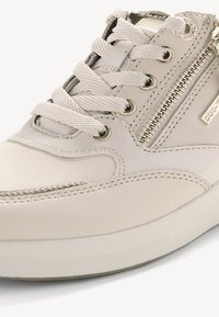 Valge nahast tennis jalanõud tekstureeritud aktsentidega, paelaga sulgemine, külgsalv ja kummist põhi. Omab õmblustead ja metallist brändimist.