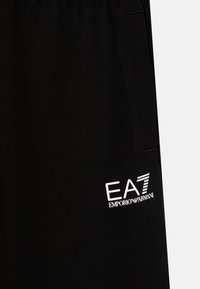 Schwarze Sportshorts aus einem glatten Stoff, mit einem weißen EA7 Emporio Armani Logo auf der Vorderseite und seitlichen Taschen.