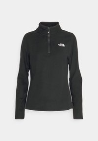 Svart fleece-pullover med halvdragkedja, långa ärmar och vit logotyp på vänster bröst. Slät textur och figurnära design.