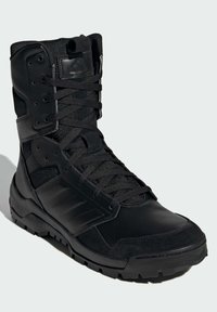 Black tactical boot with a synthetic upper, textured panels, lace closure, padded collar, and rubber outsole featuring deep treads.