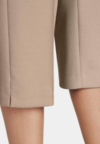 Beige geribbelde stof culottes met een rechte pasvorm, voorzien van zijsplitten aan de zoom en een gestructureerd oppervlak.