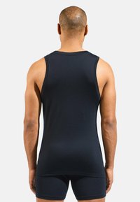 Black tank top made from a smooth, stretchy fabric, featuring a sleeveless design and a slightly elongated back hem.
