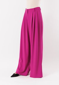 Pantaloni fucsia a gamba larga con pieghe, realizzati in tessuto morbido. Presentano una vita piatta e passanti per cintura, abbinati a décolleté nere a punta.