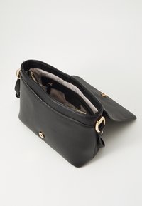 Sac à bandoulière en cuir noir avec une surface texturée, quincaillerie dorée, une poche zippée et un intérieur en tissu à motifs. Comprend un rabat de fermeture.