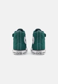 Zielone wysokie trampki na płótnie z białą gumową podeszwą, z czarno-białymi paskami oraz klasycznymi łatkami z logo Converse.