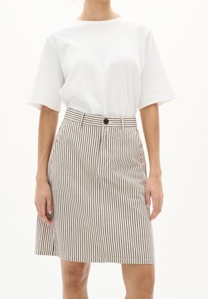 Wit T-shirt met korte mouwen, gecombineerd met een lichtbeige rok met verticale zwarte strepen, een knoopsluiting aan de voorkant en zijzakken.