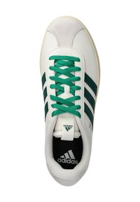 Zapatilla blanca de Adidas con cordones verdes y tres rayas verde oscuro, logo visible en la lengüeta y plantilla negra.