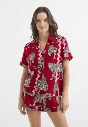 Completo pigiama rosso composto da una camicia a maniche corte con colletto e pantaloni corto, decorato con stampe leopardate in bianco e nero e motivi a onda rosa.