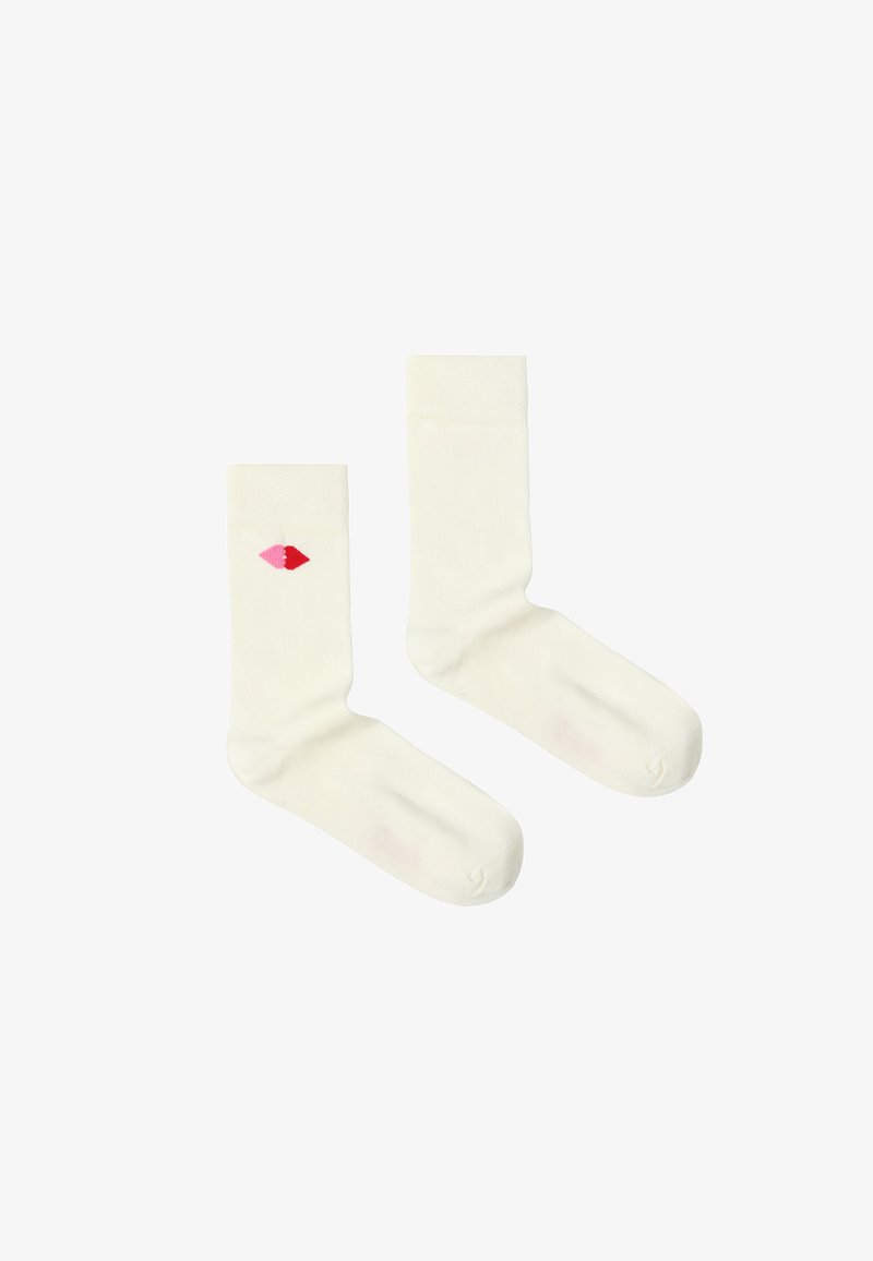 Paire de chaussettes blanches montantes, une chaussette présente un petit motif de cœur rouge et rose sur le côté extérieur près du haut.