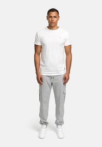 White cotton T-shirt paired with light grey cargo sweatpants featuring pockets, worn with white sneakers. Simple, casual outfit.