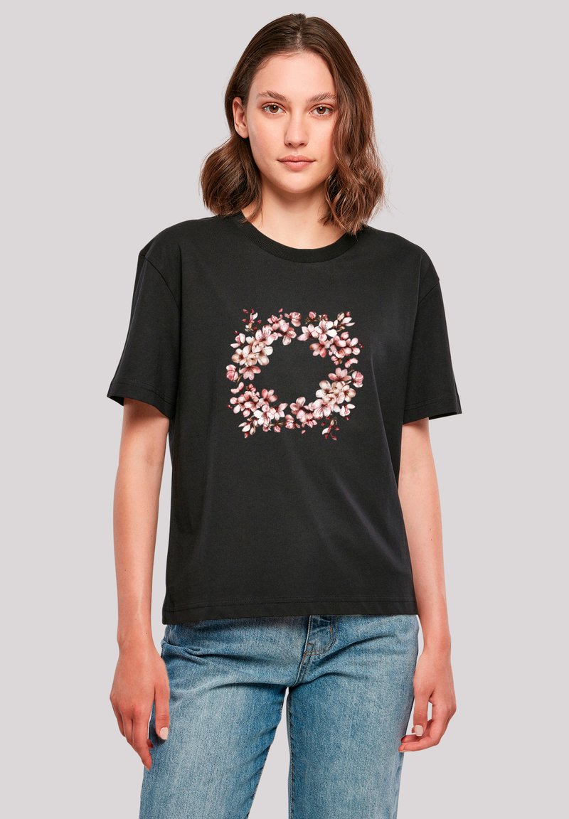 Black short-sleeve t-shirt featuring a floral design in pink and white, set within a circular arrangement. Cotton material with a relaxed fit.