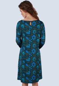 Blumendruckkleid mit langen Ärmeln, das in Blau- und Grüntönen gehalten ist, mit einem Schlüssel-Detail im Rücken und einer entspannten A-Linie-Silhouette.