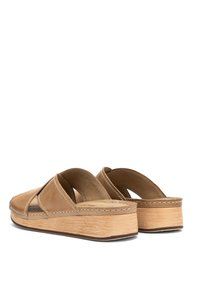 Brązowe skórzane sandały na platformie z krzyżowym zapięciem, wyściełanym wnętrzem i fakturowaną drewnianą podeszwą. Detale przeszycia na brzegach.