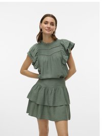 Robe verte à couches avec un tissu texturé. Présente un col et des manches froncés, avec un corsage ajusté et une jupe évasée.