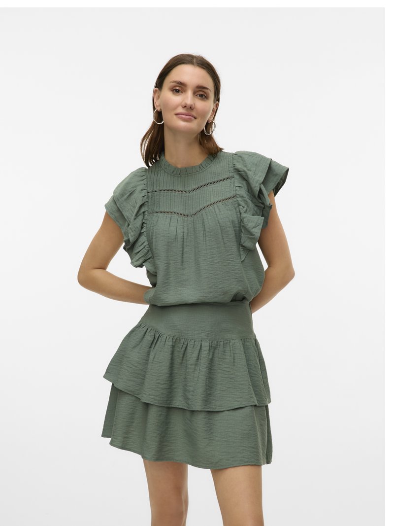 Robe verte à couches avec un tissu texturé. Présente un col et des manches froncés, avec un corsage ajusté et une jupe évasée.