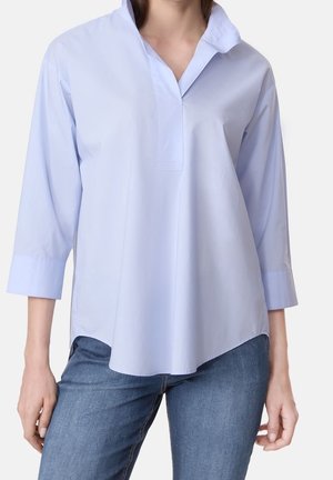 Chemise collerette bleu clair à manches longues avec une coupe décontractée et des fentes latérales, en tissu lisse, présentant un design à demi-boutonnage.
