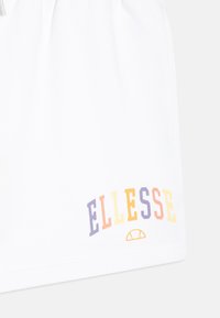 Pantalones cortos blancos de tejido suave, con un colorido logotipo de "ELLESSE" en púrpura, naranja, amarillo y rosa. Detalle de cintura con cordón.