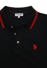 Polo noir avec des bordures rouges sur le col, un petit logo rouge brodé et trois boutons blancs sur la patte.