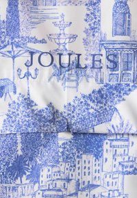 Sinine toile-muster, mis kujutab välikohviku stseeni ja linnapilti koos puude ja hoonetega, teksti "JOULES" kangale üle trükituna.