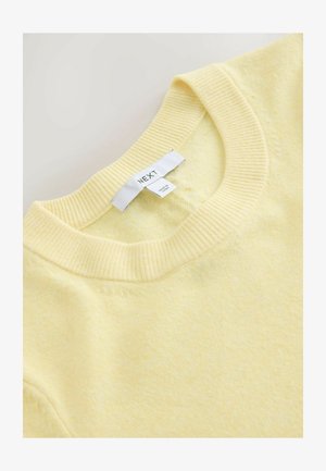 Gul trøje med ribbet rund halsudskæring, lavet af blødt materiale, med en label med teksten "NEXT" og en glat overflade.