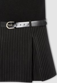 Gonna nera con sottili righe bianche verticali, caratterizzata da un design a pieghe e una cintura nera in pelle con fibbia argentata.