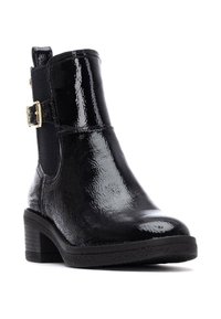 Zwarte enkelboot met een glanzende lakafwerking, elastische zijkanten, gouden gespdetails en een gestapelde hak voor extra hoogte.