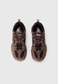 Zapatillas marrones y negras con materiales de malla y ante, que cuentan con una suela texturizada, cordones en contraste y una puntera reforzada.