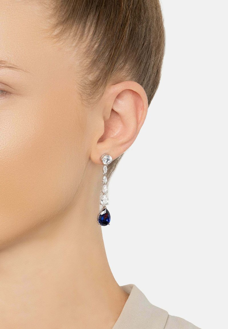 Pendientes colgantes con piedras preciosas claras y de un azul profundo, con un acabado en tono plateado, que presentan una forma de lágrima y un detallado intrincado.