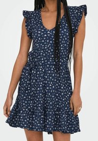 Marineblaues Kleid mit weißem Blumenmuster, Rüschensaum, V-Ausschnitt, taillierter Taille und einem schichten, ausgestellten Rock. Weicher Stoff.