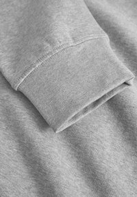 Gray sweatshirt fabric featuring a folded cuff. The texture is soft and smooth, with a subtle heather pattern throughout.