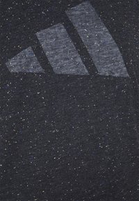 T-shirt grigio scuro con una texture a macchie, caratterizzato da un grande design grafico a tre strisce grigio chiaro sulla parte anteriore.
