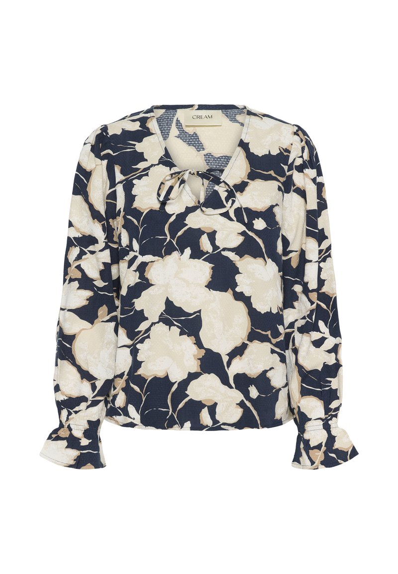 Blouse navy avec motif floral crème, présentant un décolleté en V avec un nœud, des manches bouffantes et des poignets élastiques, fabriquée dans un tissu léger.