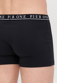 Black cotton boxer shorts with a soft waistband featuring "PIER ONE" in white lettering. Smooth texture with a fitted design.