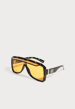 Lunettes de soleil rectangulaires surdimensionnées avec verres ambrés, monture écaille foncée et détail logo doré sur les branches.