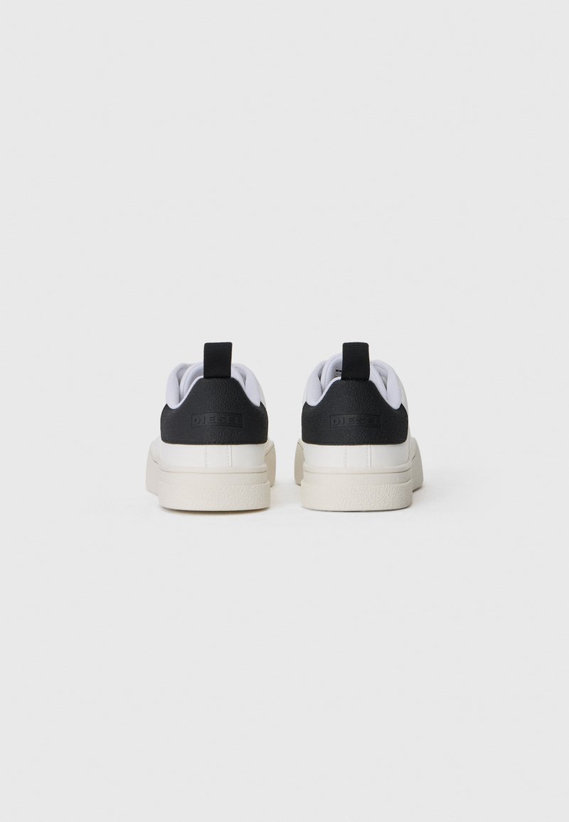 Des baskets noir et blanc présentent un dos texturé noir, un devant lisse blanc et une semelle de couleur crème. Inclut une languette au niveau du talon.
