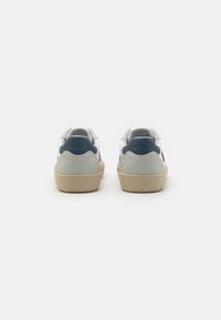 Sneakers bianchi con tomaia in pelle liscia, tallone in suede grigio e accenti blu navy. Presentano una suola in gomma beige texturizzata e un colletto imbottito.