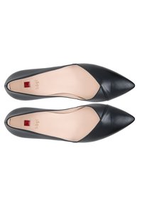 Paire de ballerines en cuir noir à bout pointu avec semelles intérieures beige et détail logo carré rouge sur la zone du talon.