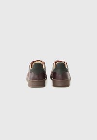Bordeaux lær sneakers med grønne accenter, der har en struktureret brun gummisole og et minimalistisk bagsidedesign.
