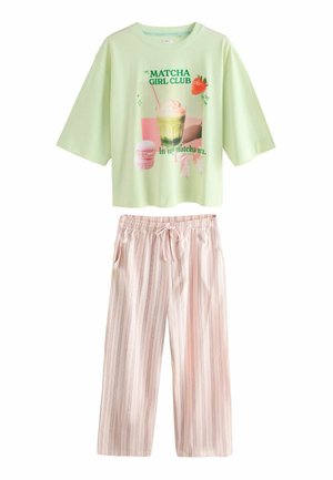 Hellgrünes Kurzarmoberteil mit „Matcha Girl Club“-Grafik, kombiniert mit lockeren, hellrosa gestreiften Hosen mit Kordelzug.