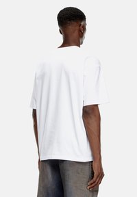 Hvid bomulds T-shirt med korte ærmer, rund hals og en afslappet pasform. Glat tekstur uden synlige mønstre eller detaljer.