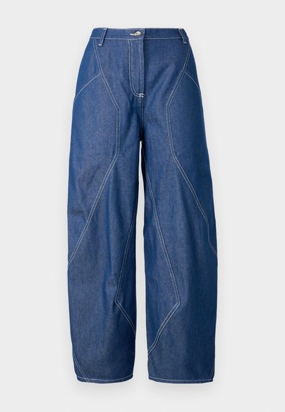 Calças de ganga de perna larga em azul escuro com costura branca em contraste. Apresentam um fecho de botão e uma cintura alta, com detalhes de costura angulares.