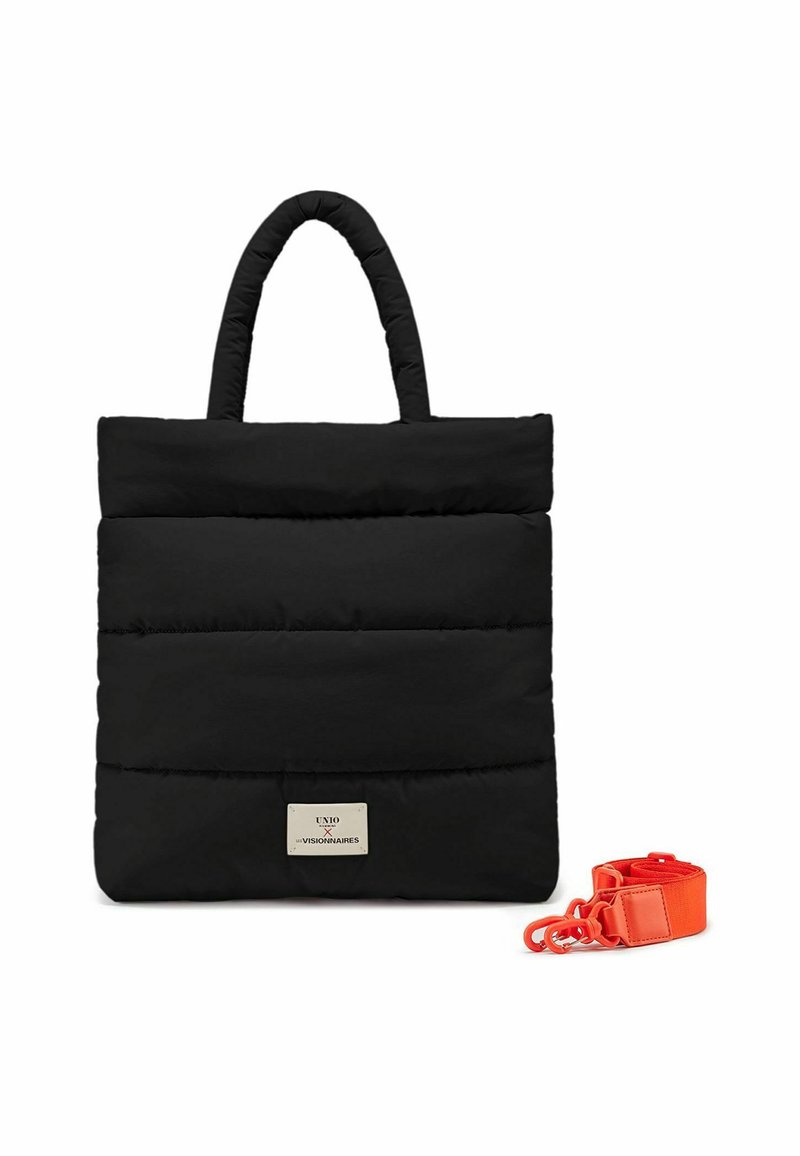 Sac fourre-tout noir rembourré avec deux poignées, présentant une plaque logo dorée et une sangle amovible orange sur le côté. Texture lisse, design minimaliste.