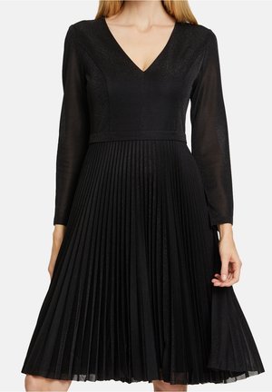 Schwarzes Kleid mit V-Ausschnitt, langen transparenten Ärmeln und einem plissierten Rock. Hergestellt aus einem strukturierten Stoff mit dezentem Schimmer.