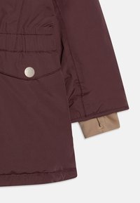 Mørkerød dynejakke med beige foring, elastisk talje og sølvfarvet trykknaplukning for ekstra detaljer. Blødt, tekstureret stof.