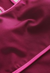 Fuksia uima-allas yläosa, jossa on sileä, joustava kangas ja vaaleanpunaiset korostukset reunoilla ja hihnoissa, korostaen istuvaa muotoilua.