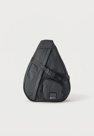 Czarna torebka na ramię w kształcie kropli z regulowanym paskiem i przednią kieszenią na zamek z małą naszywką z logo marki.