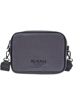 Rektangulær sort crossbody-taske med justerbar strop, lynlåslukning og teksten "KANI The Original EST. 1989" på forsiden i midten.
