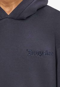 Ciemnoszara, oversize bluza z kapturem wykonana z miękkiego materiału, z przednią kieszenią i haftowanym logo "Dropsize" w ciemniejszym odcieniu.