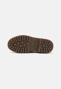 Sola de bota de borracha castanha com profundos sulcos para tração. Apresenta um design hexagonal central e a marca Timberland perto do calcanhar.